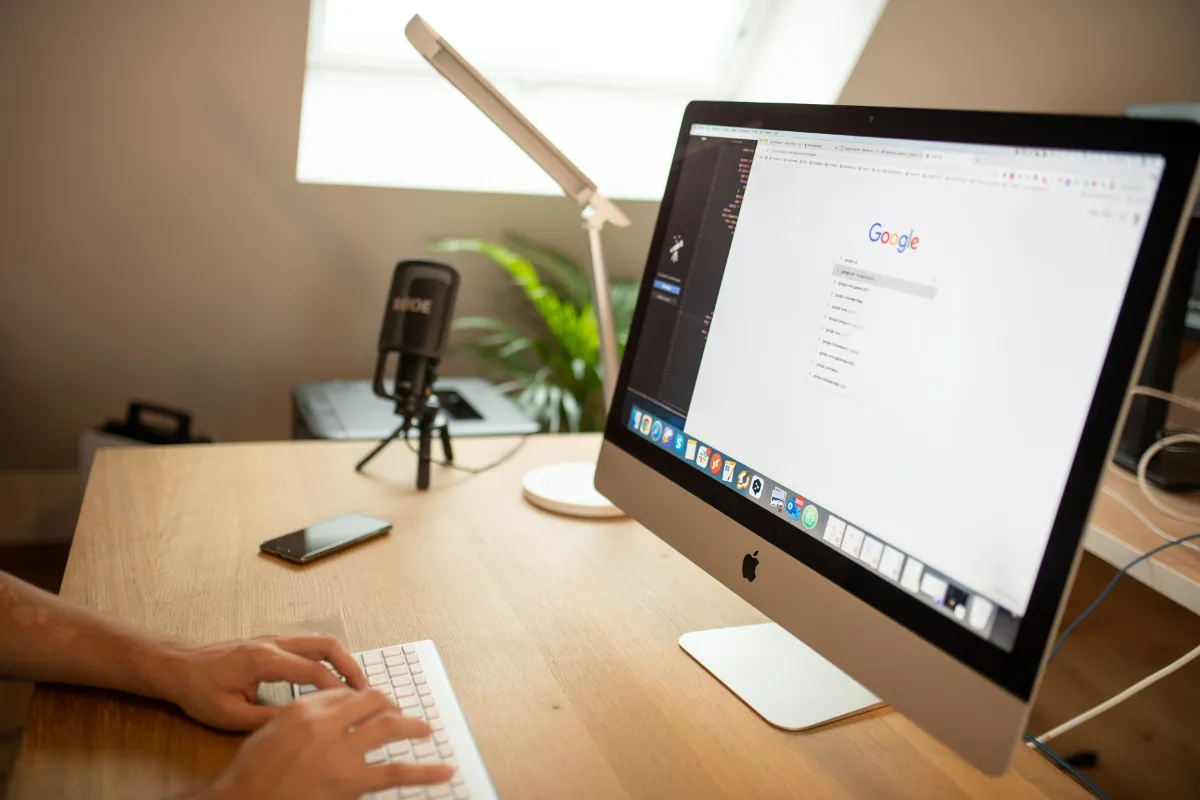 A person typing at a desktop computer showing a search page
